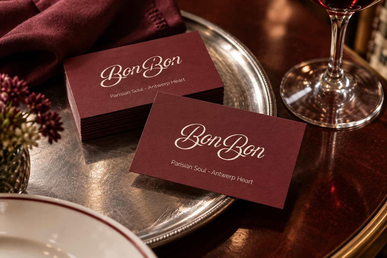 Bonbon-visitekaarten in bordeaux en crème, gepresenteerd op een zilveren dienblad